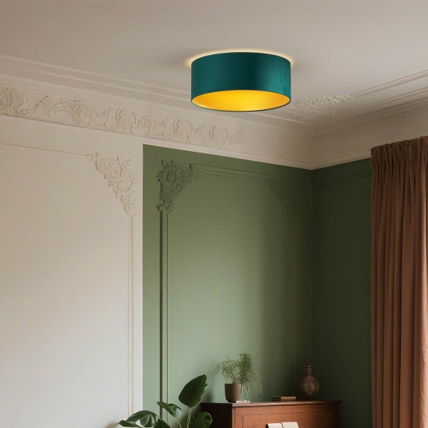 Zylindrische Deckenleuchte mit dunkelgrünem Textilschirm und goldfarbenem Inneren an einer verzierten Decke in einem klassischen Raum.