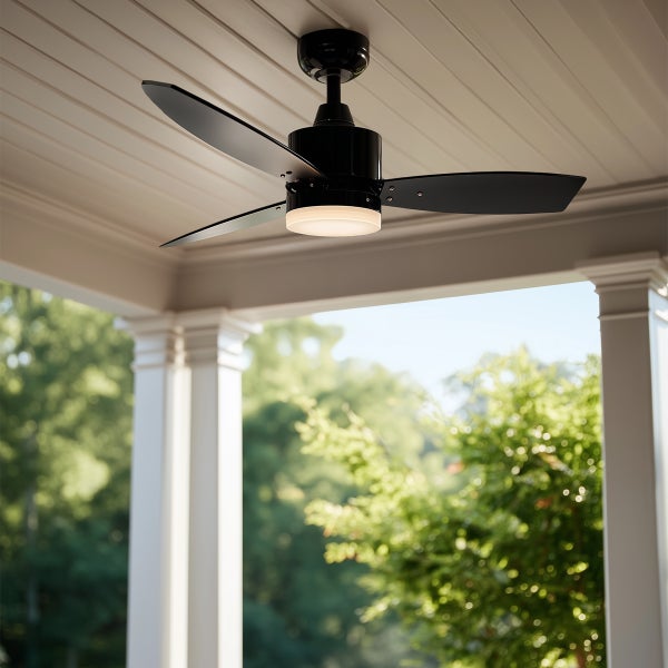Moderner schwarzer Deckenventilator mit drei Flügeln und integrierter Leuchte an einer weißen Paneeldecke auf einer hellen Terrasse.