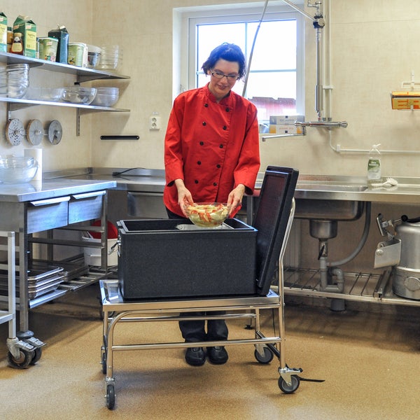Frau in Küche befüllt Transportwagen mit Schüssel mit geschnittenen Äpfeln