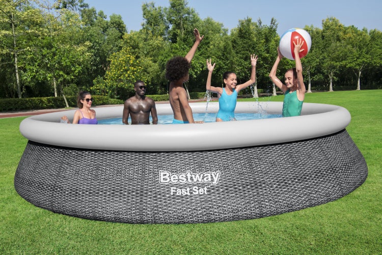 Bestway Fast Set Pool in Rattan-Optik auf einer Rasenfläche, Familie und Kinder spielen mit einem Wasserball im Wasser, Gartenszene.