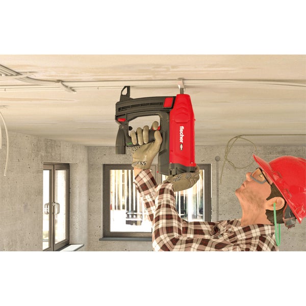 Handwerker befestigt eine Leitung mit einem Bolzenschussgerät von Fischer an der Decke