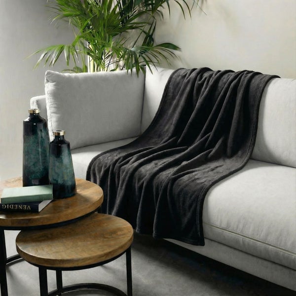 Graue Kuscheldecke auf einem Sofa mit Beistelltisch und Dekoration