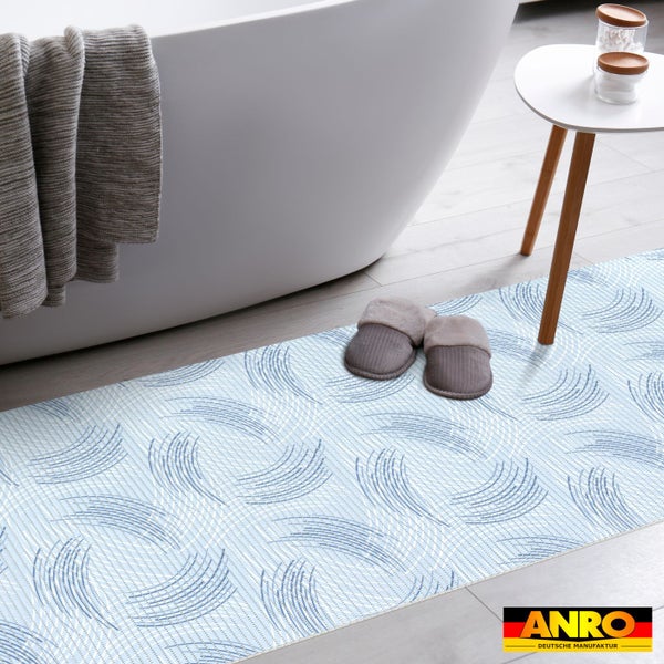 Moderner Badläufer mit blau-weißem Wirbelmuster im Badezimmer neben einer Badewanne und einem Beistelltisch. ANRO Deutsche Manufaktur Logo.