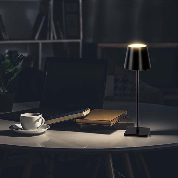 Dekorative Tischleuchte auf einem Schreibtisch mit Laptop und Büchern