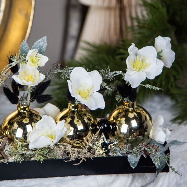 Dekoration mit goldenen Vasen, weißen Blüten, Sternen und Tannenzweigen in einer schwarzen Schale.