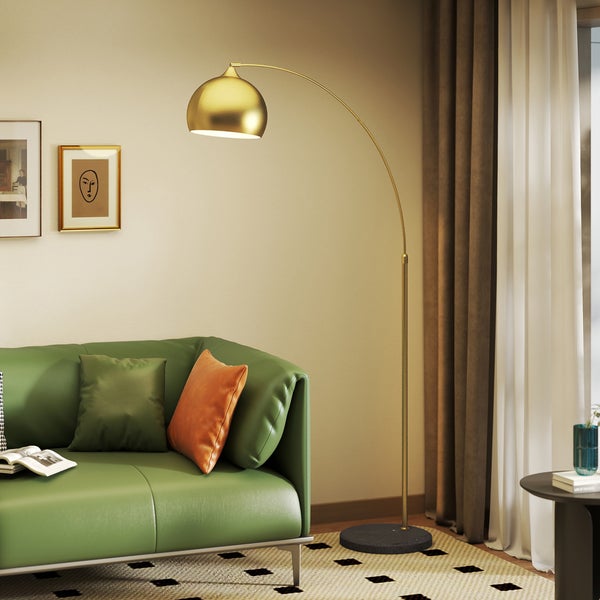 Moderne goldene Bogenlampe über einem grünen Sofa in einem hellen Wohnzimmer.