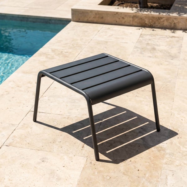 Moderner, quadratischer Gartenhocker aus Metall mit Lamellen auf einer Steinterrasse am Pool.