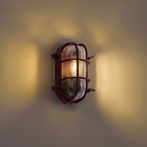 Ovale Außenwandleuchte mit Schutzgitter und geriffeltem Glas für eine stimmungsvolle Beleuchtung.
