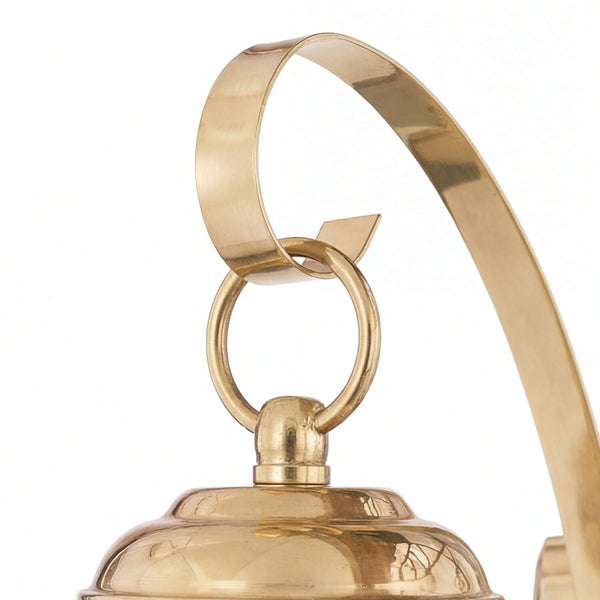 Detailaufnahme einer goldenen Außenleuchte mit Aufhängung.