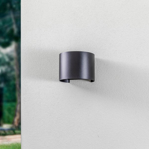 Moderne, halbkreisförmige Außenwandleuchte in Anthrazit an einer hellen Fassade.