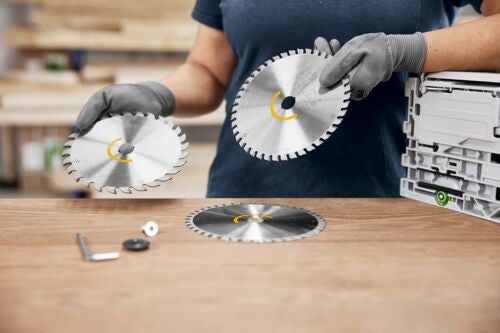 Person hält Kreissägeblätter, Zubehör auf Holztisch