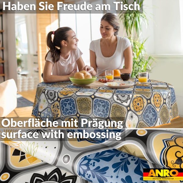 Runde Tischdecke aus geprägtem Wachstuch mit Fliesenmuster in einer hellen Esszimmerszene mit Mutter und Tochter. ANRO DEUTSCHE MANUFAKTUR Logo.