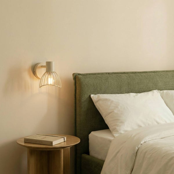 Wandleuchte neben einem Bett mit Nachttisch.
