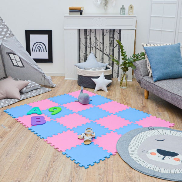 Schaumstoff-Puzzlematte für Kinder in Blau und Rosa auf hellem Holzboden in einem hellen, modern eingerichteten Kinderzimmer mit Spielzelt.