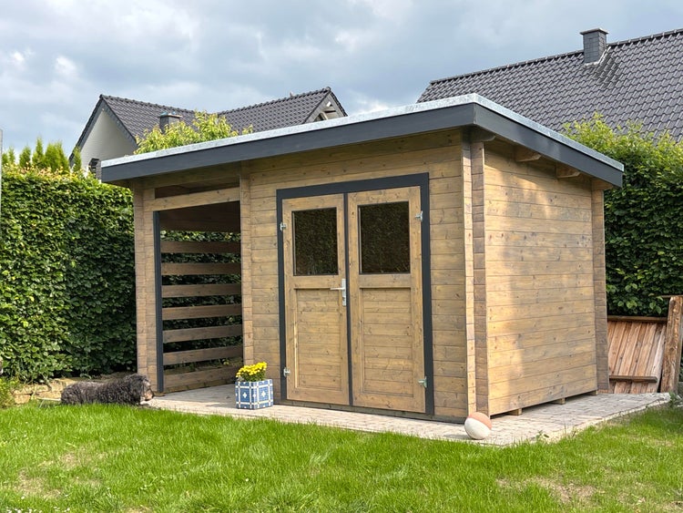 Modernes Gartenhaus aus Holz mit Pultdach, integriertem Unterstand mit Lamellenwand und Doppeltür mit Glaseinsätzen im Garten.