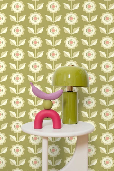 Szene mit Tischleuchte und Dekoration auf einem kleinen Tisch vor einer gemusterten Tapete