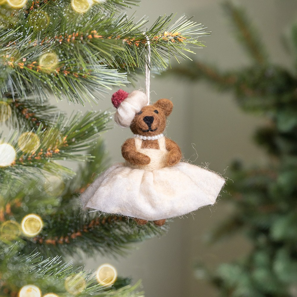 Teddybär als Christbaumschmuck mit Kleid und Kopfbedeckung am Weihnachtsbaum