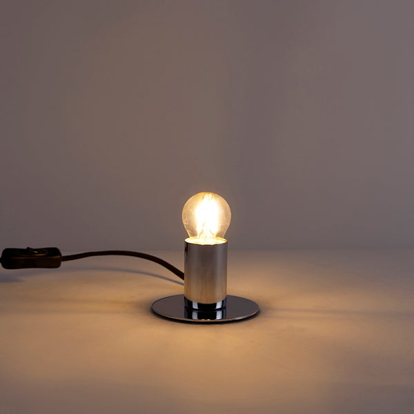 Tischleuchte aus verchromtem Metall mit runder Basis und leuchtender Glühbirne, inklusive Schnurschalter.