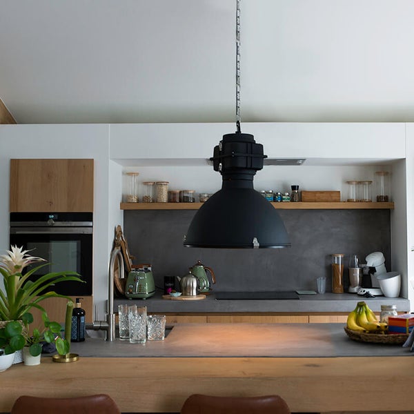 Moderne Küche mit Hängelampe, Küchengeräten und Lebensmitteln in Gläsern.