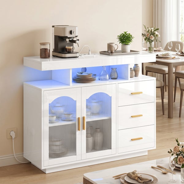 Modernes Sideboard in Weiß Hochglanz mit integrierter LED-Beleuchtung, zwei geriffelten Glastüren und drei Schubladen mit goldfarbenen Griffen.