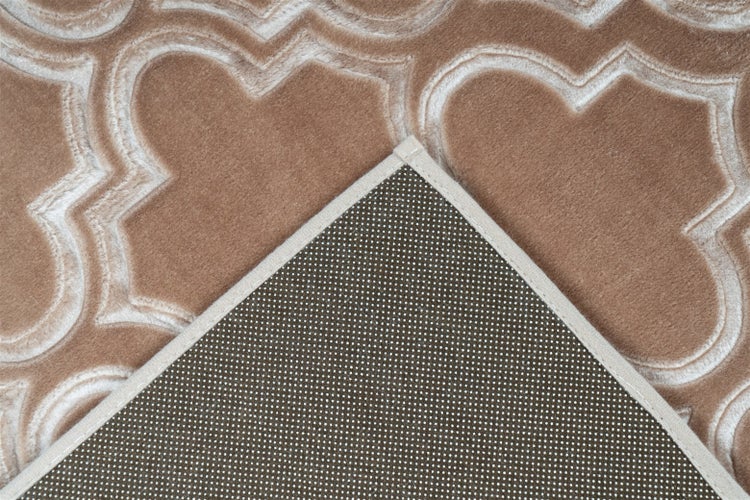 Detailansicht eines Teppichs mit geometrischem Muster und umgeschlagener Ecke mit rutschhemmender Rückseite.
