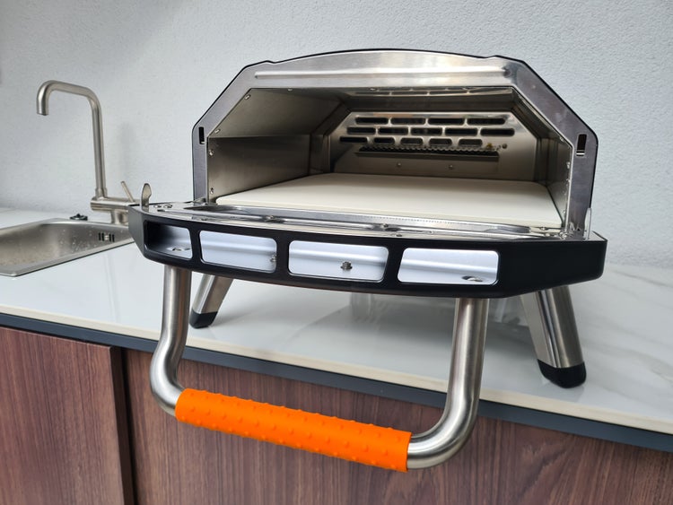 Pizzaofen mit offener Front und Pizzastein im Innenraum.