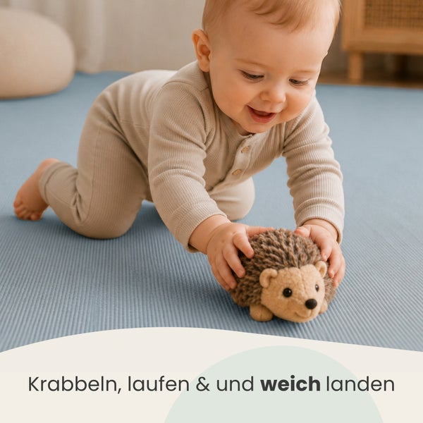 Kleinkind krabbelt auf einer weichen Spielmatte und spielt mit einem Stoffigel.