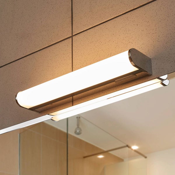 Moderne LED-Badezimmer-Spiegelleuchte mit Chrom-Elementen, montiert auf einem Spiegel in einem hell gefliesten Badezimmer.