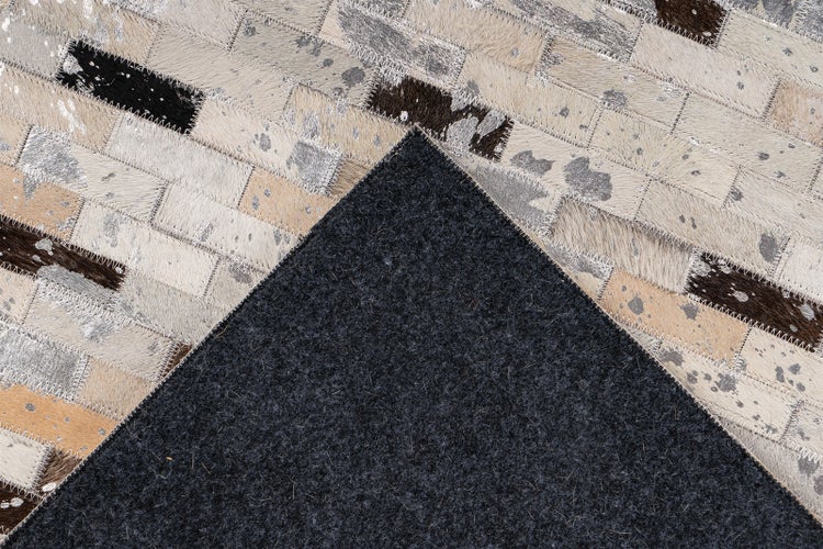 Patchwork-Teppich aus Kuhfell in Backsteinoptik mit dunkler Filzrückseite.