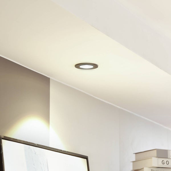 Moderner LED-Einbaustrahler in einer Decke in einem hellen, organisierten Wohnraum.