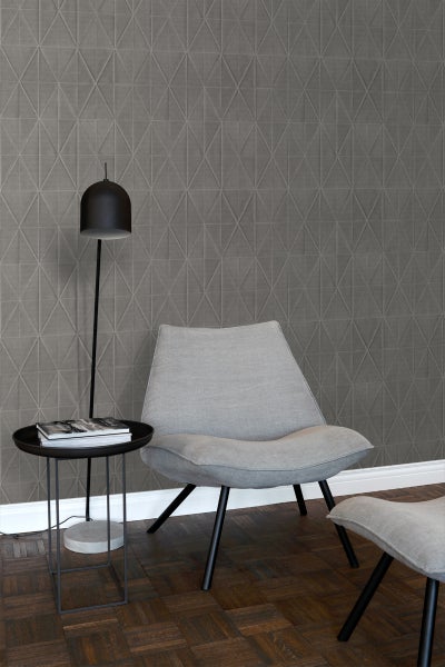 Wohnzimmer mit Sessel, Lampe und geometrischer Tapete