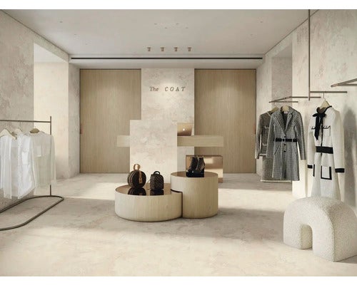 Innenansicht eines Bekleidungsgeschäfts mit Kleidern und Accessoires auf Ausstelltischen und Kleiderständern.