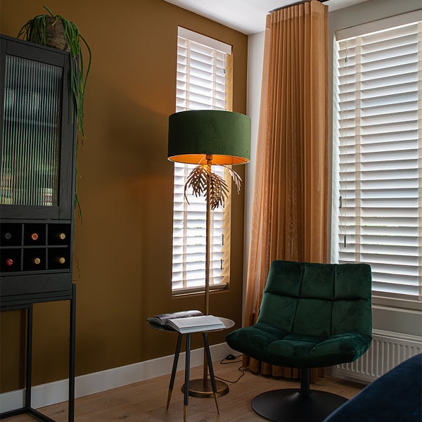 Wohnzimmer mit Schrank, Stehlampe, Sessel, Vorhängen und Jalousien