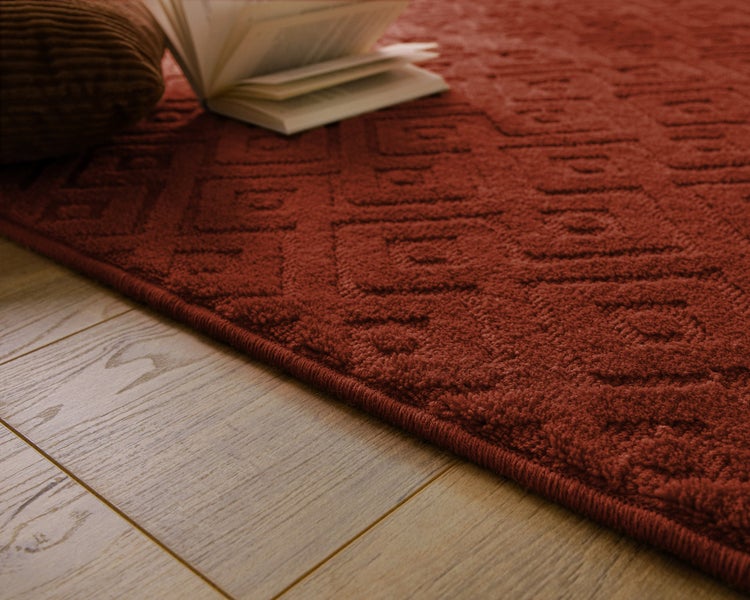 Strukturierter Teppich mit geometrischem Muster und hohem Flor auf einem Holzboden.