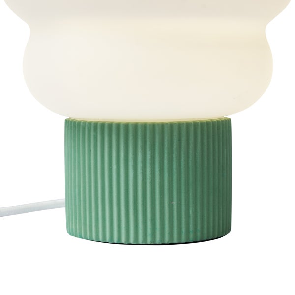 Tischleuchte mit weißem Glasschirm und grünem, geriffeltem Sockel.