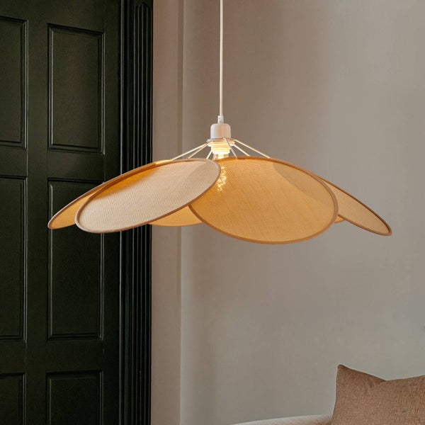 Moderne Pendelleuchte mit blütenblattförmigen Schirmen aus hellem Naturgeflecht in einem Raum vor einer dunklen Tür.