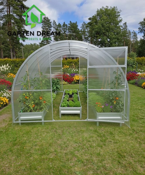 Gewächshaus mit Pflanzen und Hochbeeten im Garten