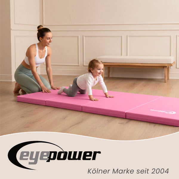 Eine Frau beaufsichtigt ein Baby, das auf einer Klappmatratze krabbelt.