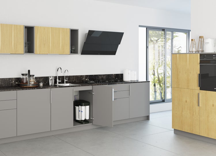 Moderne, helle Küche mit grauen Fronten, Holz-Akzenten und einem unter der Spüle eingebauten Wasserfiltersystem im offenen Unterschrank.