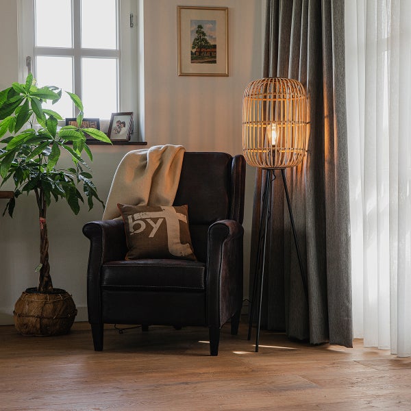 Leseecke mit Sessel, Stehlampe aus Rattan und Zimmerpflanze in Flechtkorb