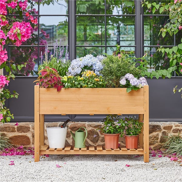 Hochbeet aus Holz mit Blumen und Gartenzubehör