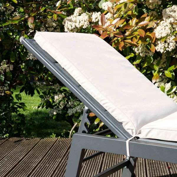 Gartenliege mit verstellbarem Rückenteil und beigefarbener Polsterauflage auf einer Holzterrasse im Garten.