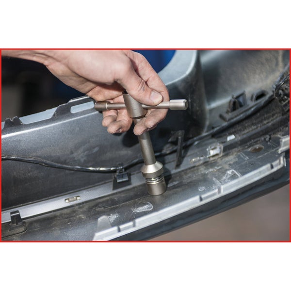 Eine Person benutzt einen T-Griff Steckschlüssel am Stossfänger eines Autos.