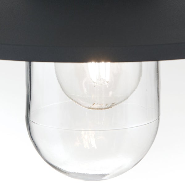 Detailansicht einer Leuchte mit schwarzem Schirm, klarem Glaszylinder und brennendem Leuchtmittel.