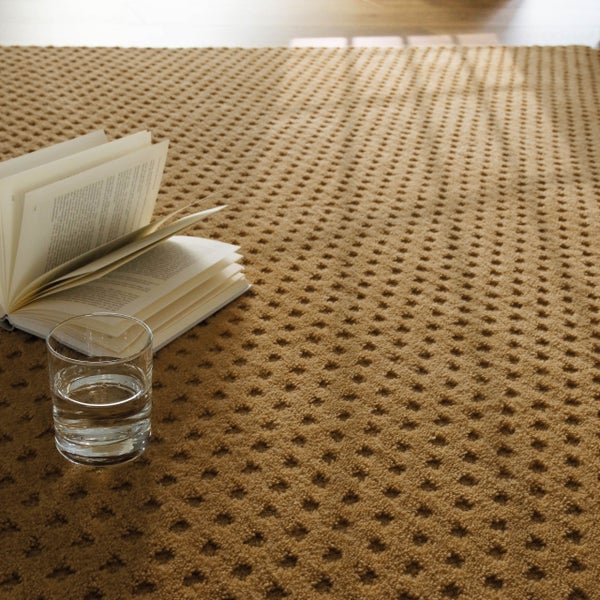 Strukturierter Teppich mit Punktmuster in einem hellen Wohnzimmer mit Sofa, Holzboden und einem aufgeschlagenen Buch.
