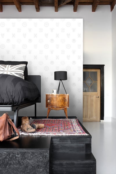 Schlafzimmer mit Bett, Nachttisch, Lampe und dekorativer Wandtapete