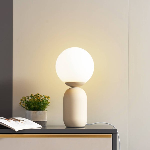 Dekorative Tischleuchte mit kugelförmigem Lampenschirm auf einem Nachttisch