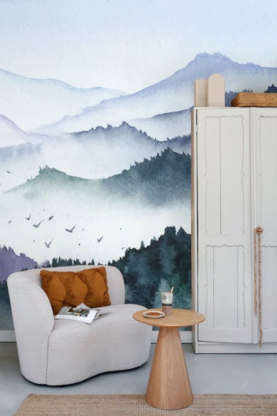 Helles Zimmer mit Sessel, Beistelltisch, Schrank und Wandbild mit Bergmotiv