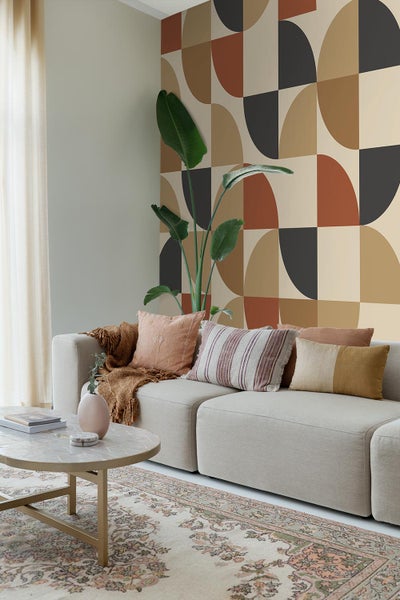 Wohnzimmer mit Sofa, Kissen, Teppich, Tisch und geometrischer Tapete