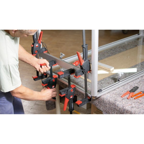 Ein Zimmermann arbeitet an einem Holzrahmen mit Schraubzwingen